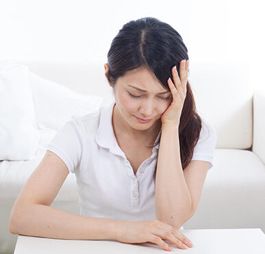 自律神経失調症の症状が辛く、頭を抱えて不調を訴えている40代女性