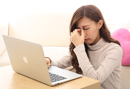 パソコンのデスクワークで目を酷使しすぎて頭痛を引き起こしている20代女性